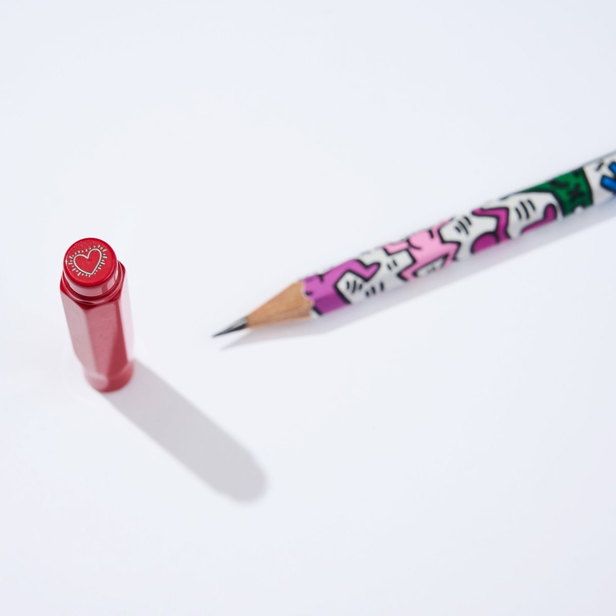 Red point guard standing upright next to a pencil with Keith Haring artwork.