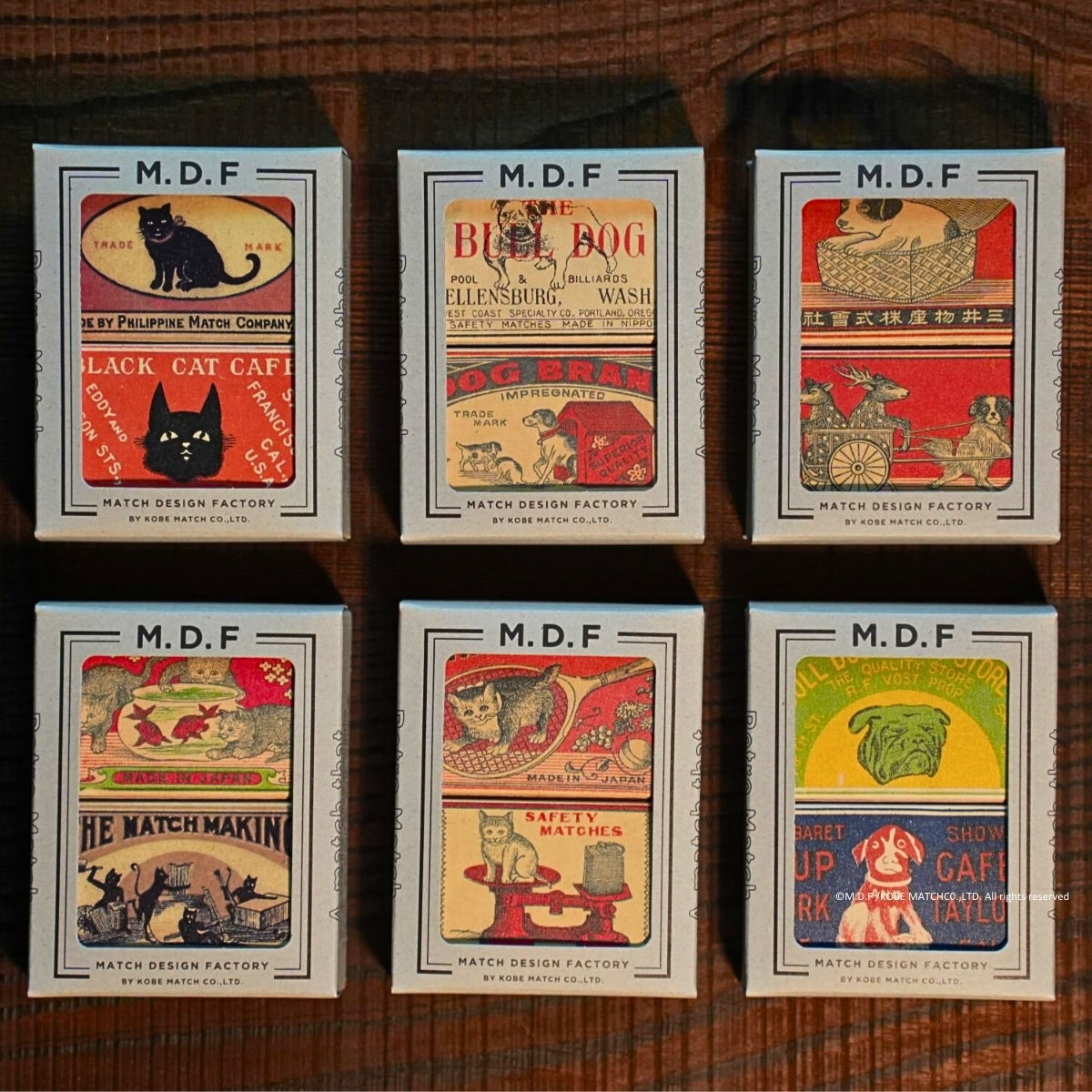 Six vintage-style matchbox labels with different illustrations and text on a wooden surface.