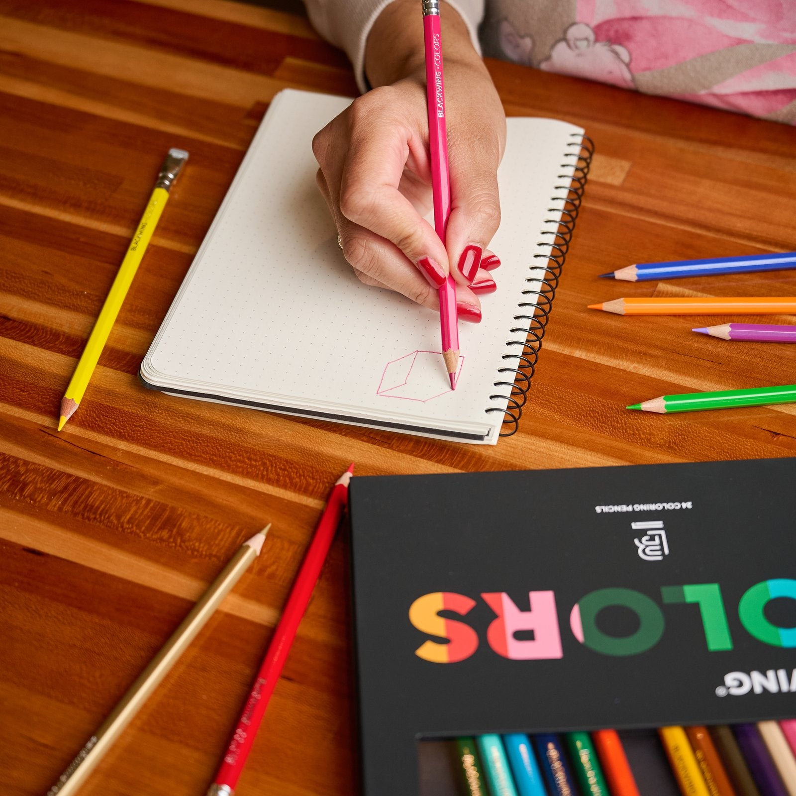Colouring in a notebook with Blackwing Colors pencils beside the COLORS box.