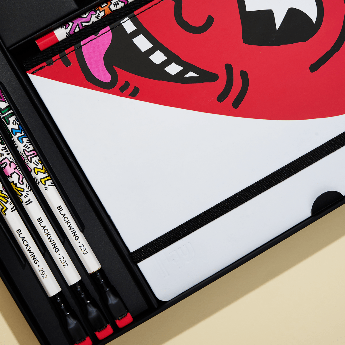 Detail of the pencils and sketchbook inside the open gift box.