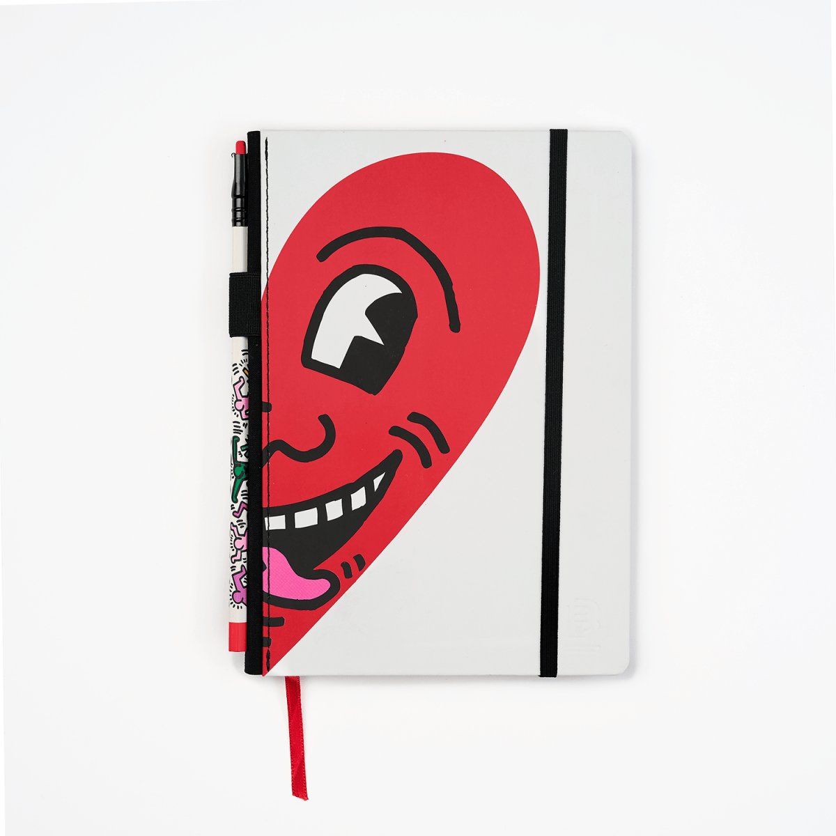 Front view of the Keith Haring “Smiling Heart” notebook featuring a bold red heart design on a white cover with black elastic closure.