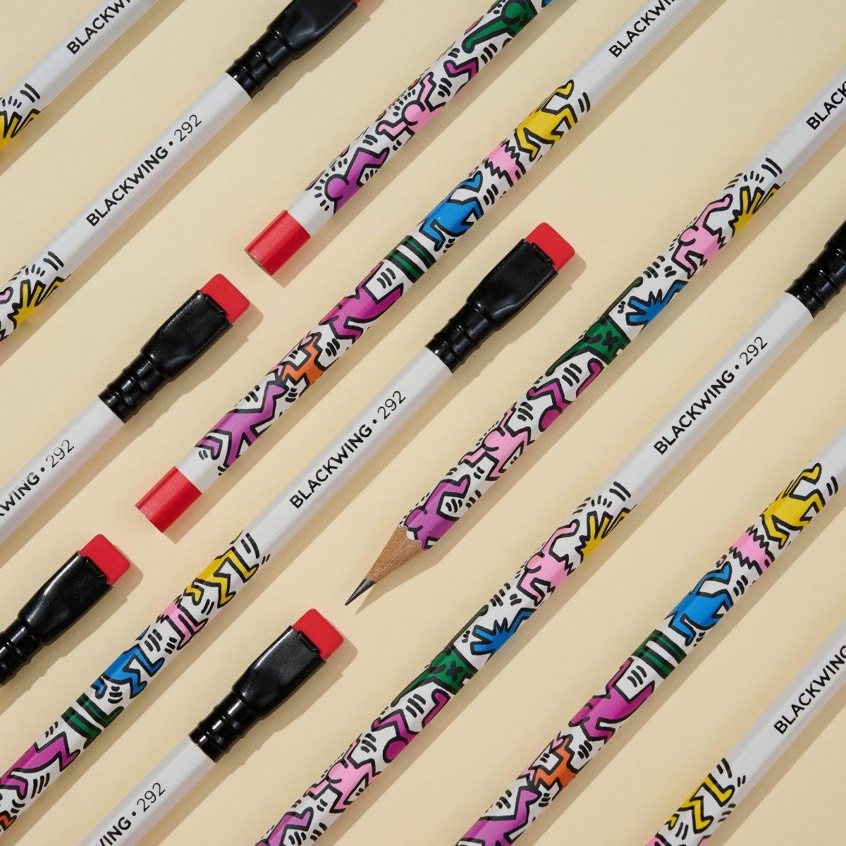 Overhead view of all twelve pencils laid out, each showcasing different segments of Haring’s colourful designs.