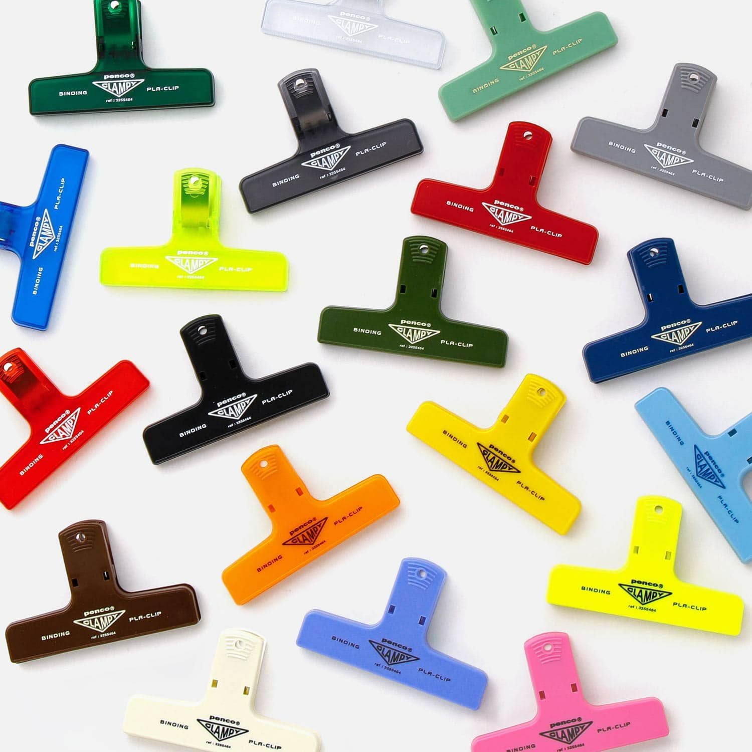 A colourful assortment of Hightide Penco Clampy Plastic Clips laid out on a white surface, showcasing a variety of retro-style colours.