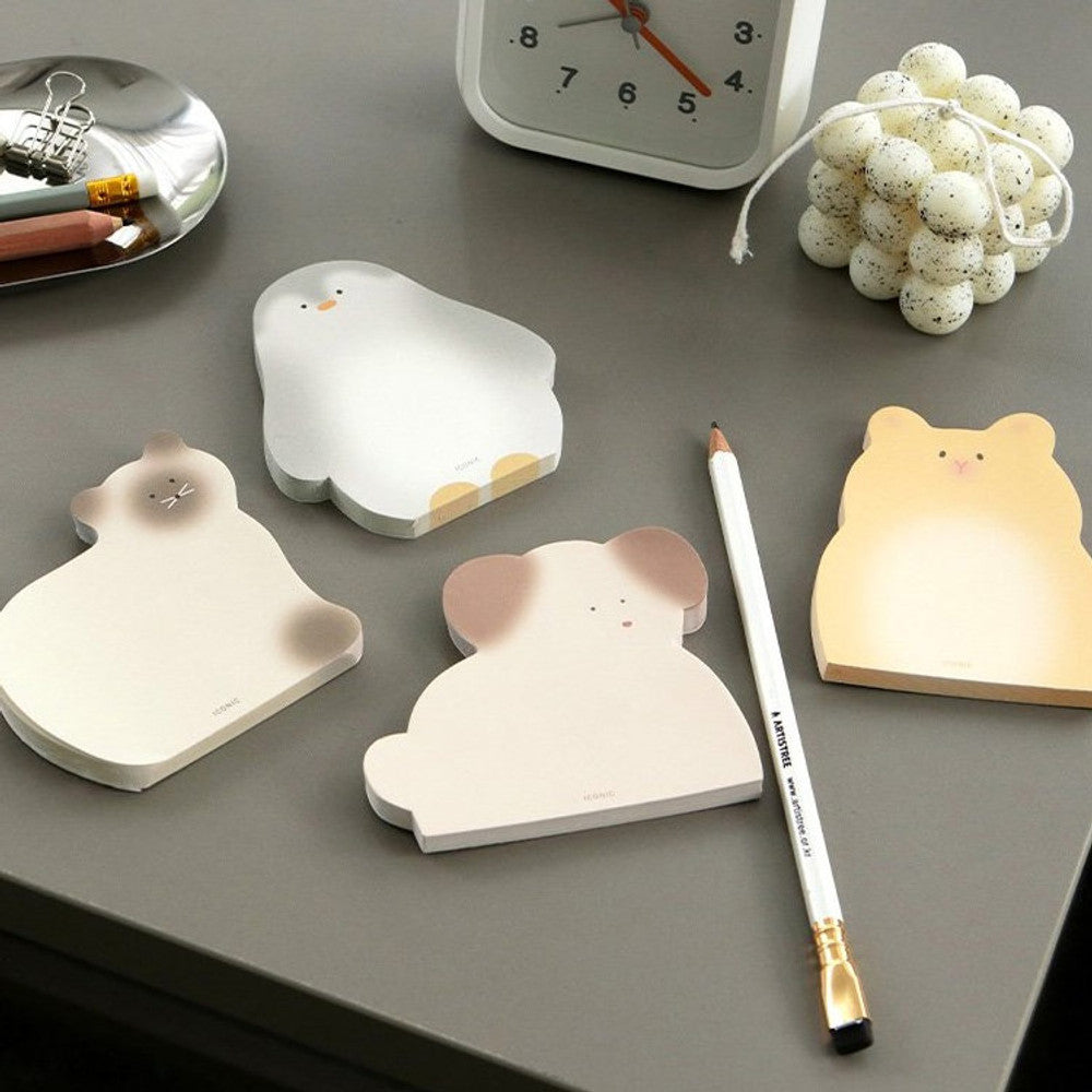 A collection of animal-shaped memo pads arranged on a dark grey desk with pens and clips for writing notes.
