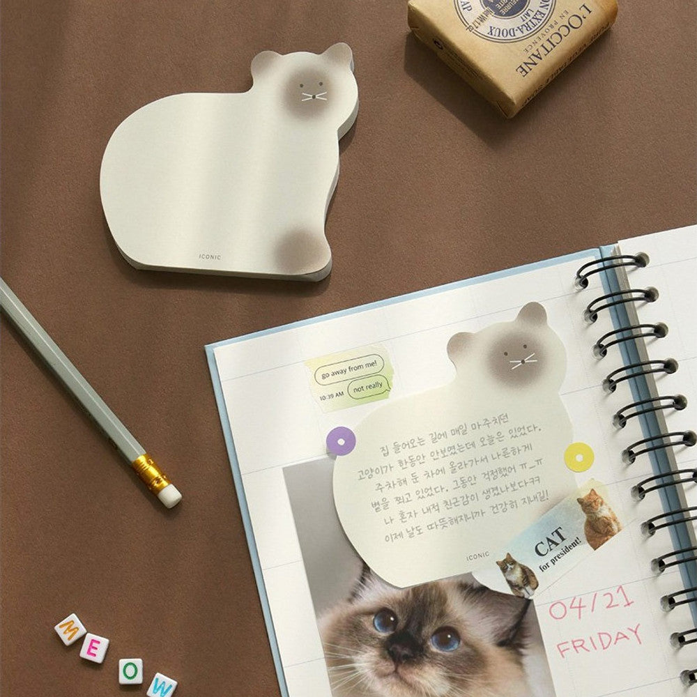 A brown cat-shaped memo pad placed beside a pencil and open planner on a tidy wooden desk.