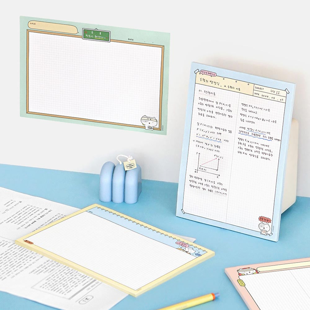 Iconic B5 Blah Blah Memo Notepad blue cover version open on desk with pencil and paper clips.