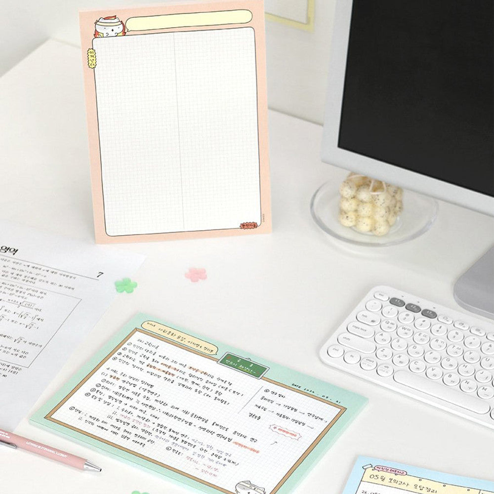 Iconic B5 Blah Blah Memo Notepad pastel orange cover version standing upright on desk with stationery beside it.