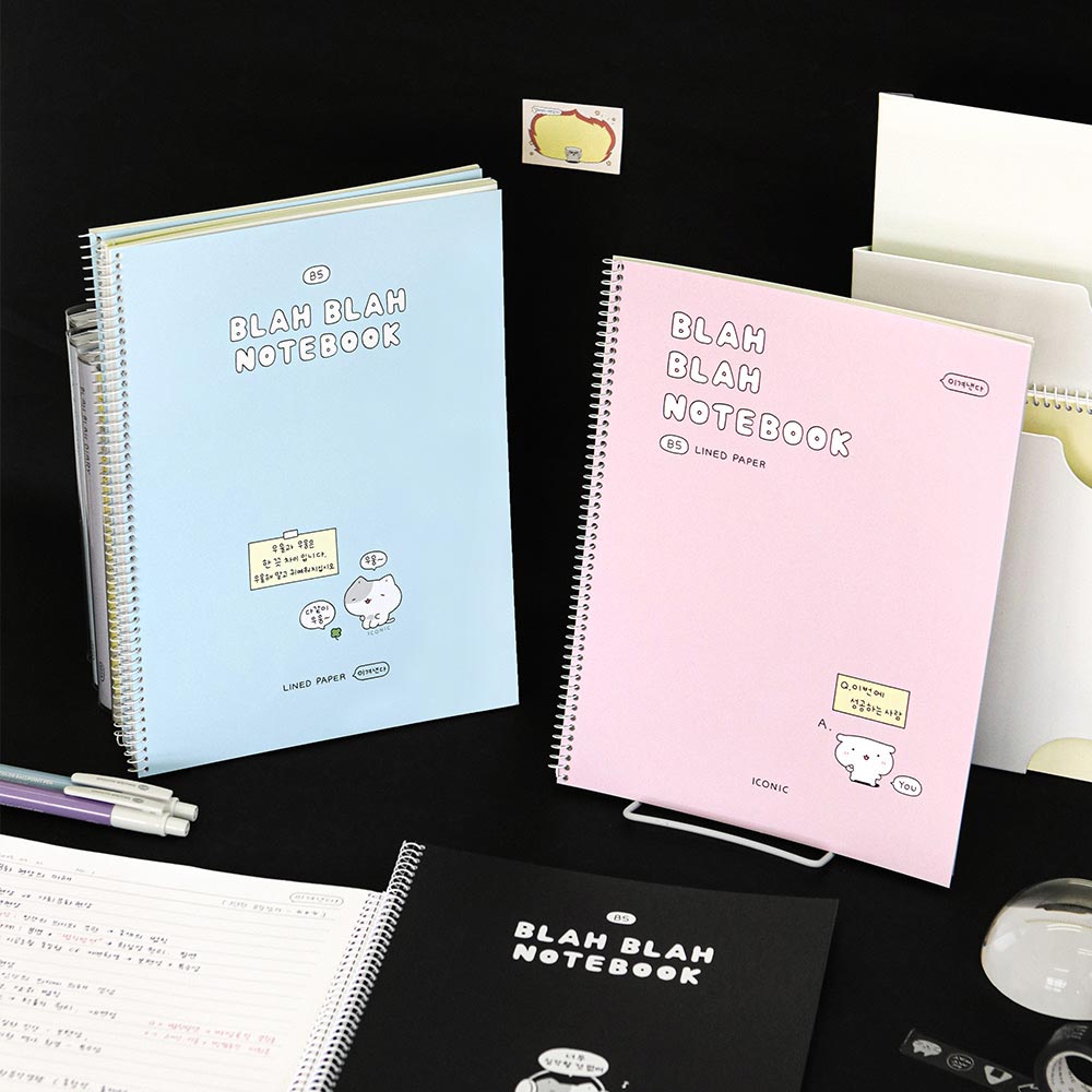 Iconic Blah Blah Spiral Lined Notebooks in pastel blue, pink, and black covers displayed with stationery on desk.