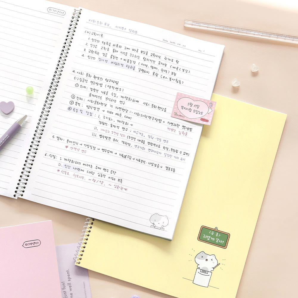 Iconic Blah Blah Spiral Lined Notebook open on desk with writing and pastel yellow notebook beneath.