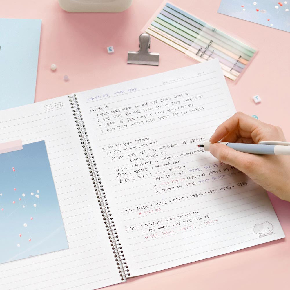 Iconic Blah Blah Spiral Lined Notebook pastel pink cover being used for note-taking with pencil.