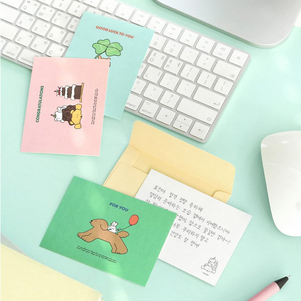 Iconic Cuddly Message Cards and envelopes arranged beside computer keyboard and stationery accessories.