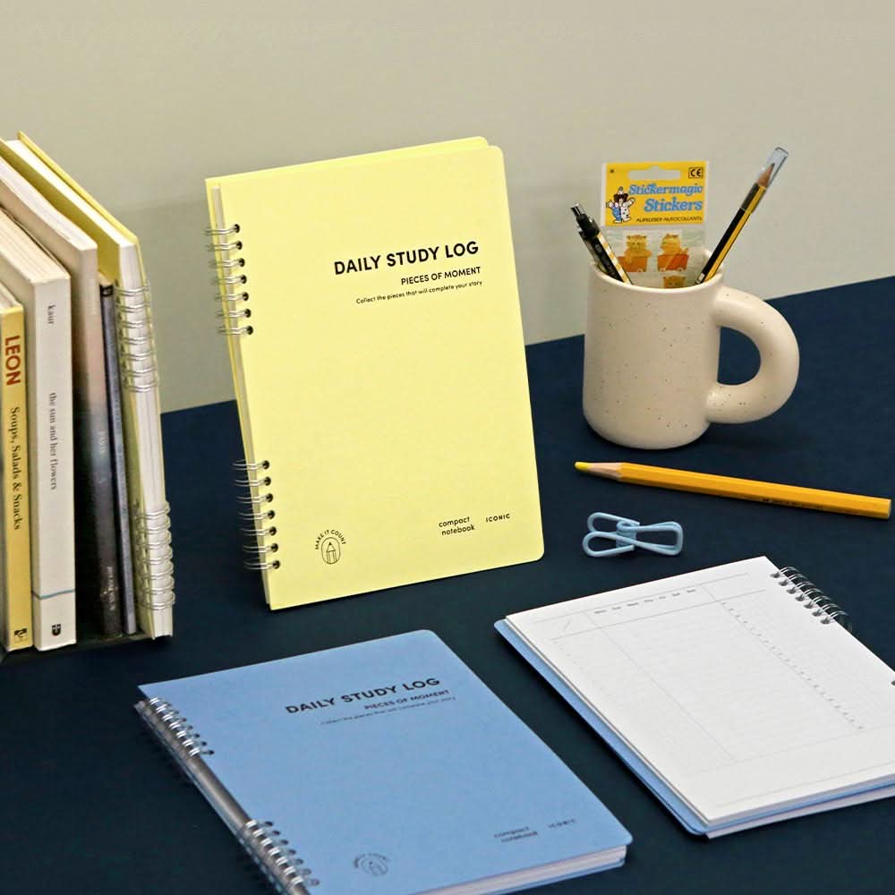 Iconic Daily A5 Study Planners in yellow and blue displayed on a desk with books, stationery, and a mug, showing their practical and stylish design.