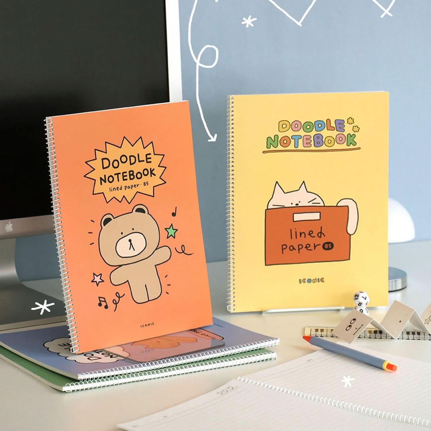 Iconic Doodle B5 Spiral Notebook in orange and yellow covers displayed on desk beside stationery.