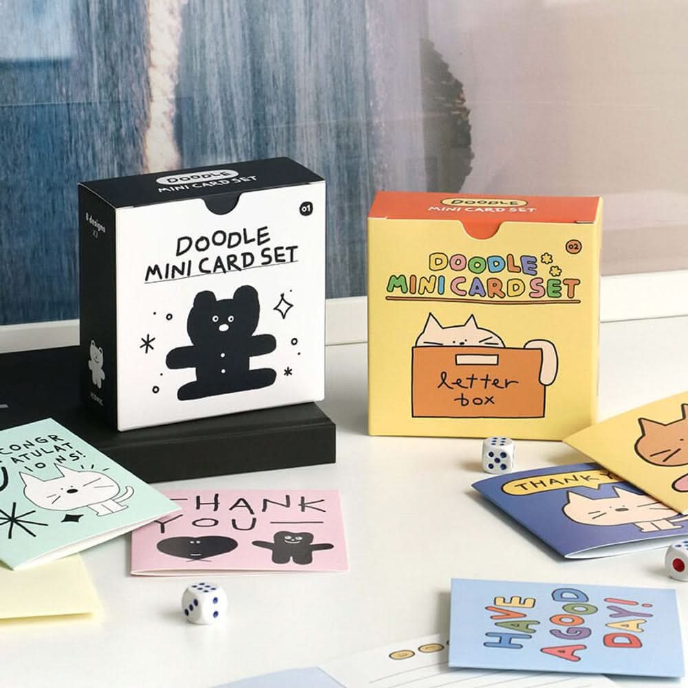 Iconic Doodle Mini Card Sets in black and yellow boxes displayed with assorted cute illustrated cards on desk.