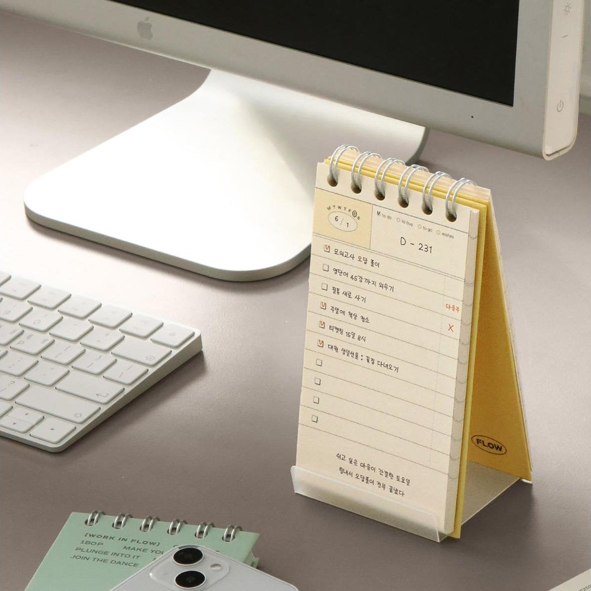 The yellow Iconic Flow Checklist displayed upright beside a keyboard and lamp, ready for daily use.