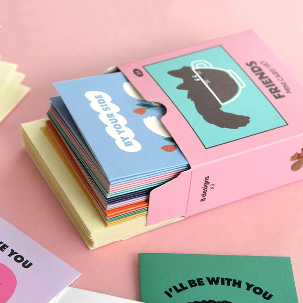 Open Iconic Mini Friends Card Set box showing stacked cards in various playful designs on pink surface.