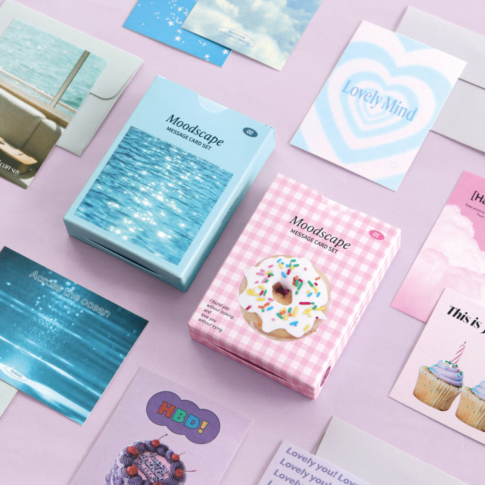 Iconic Moodscape Message Card Set in pastel blue and pink boxes with assorted cards and envelopes displayed on desk.