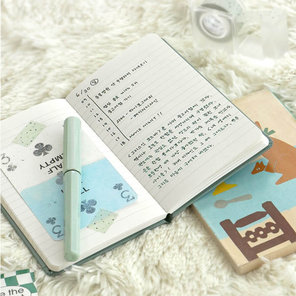 Iconic Solitude B7 Handy Notebook open with handwritten notes beside travel photos and small stationery items.