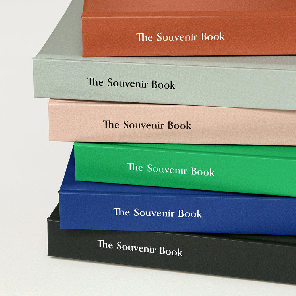 A close-up of stacked Iconic Souvenir B6 Grid Notebooks in assorted colours showing their elegant spines with embossed titles.
