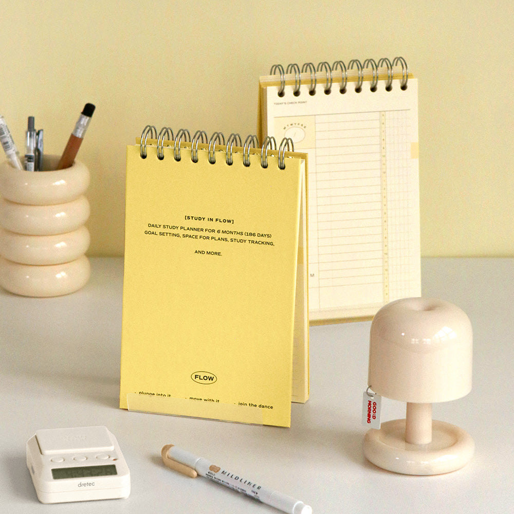 Iconic Undated Flow Spiral Study Planner in butter yellow cover displayed upright on desk with pen and stationery.