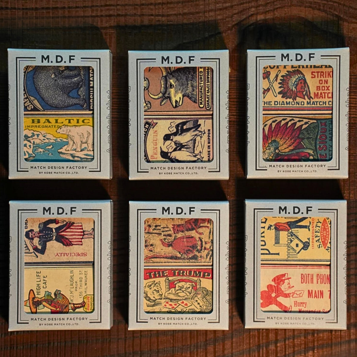Six M.D.F. Match Design Factory matchbox labels on a wooden surface